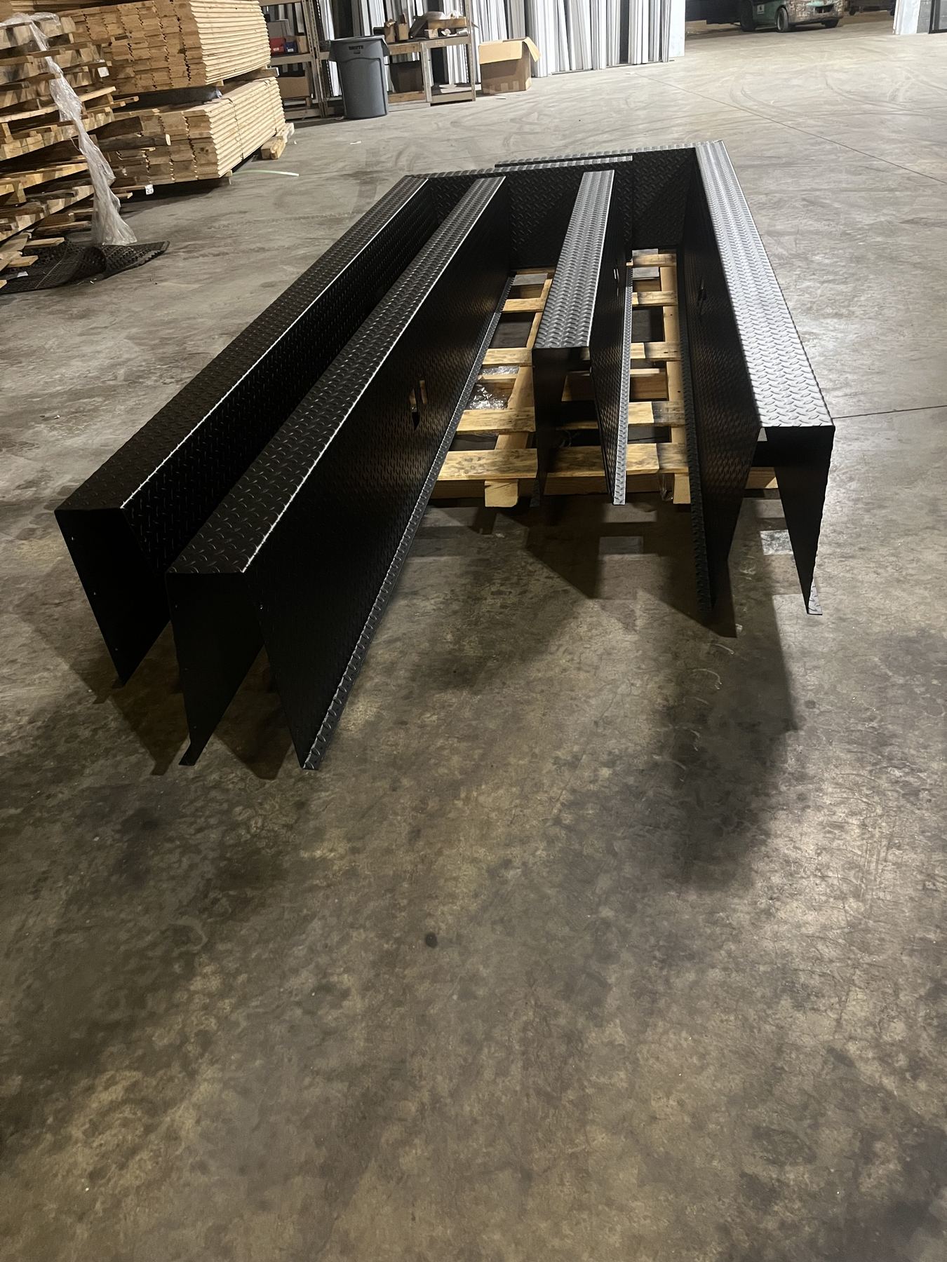 Long diamond-plate deck panels stretching across the shop floor, dwarfing the racking behind them